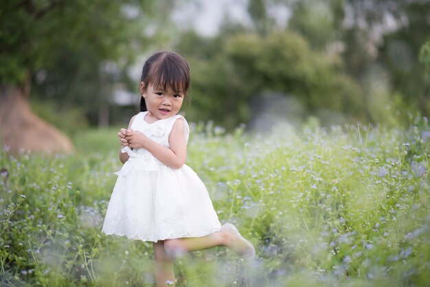 Feliz niña de pie en el prado