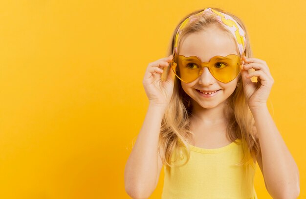 Feliz niña posando con gafas de sol