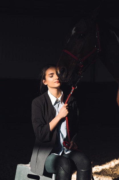 Feliz niña sentada al aire libre abrazando a su caballo