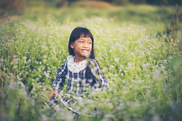 Feliz niña sentada en el prado