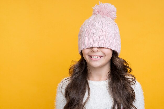 Feliz niña con sombrero rosa sobre sus ojos