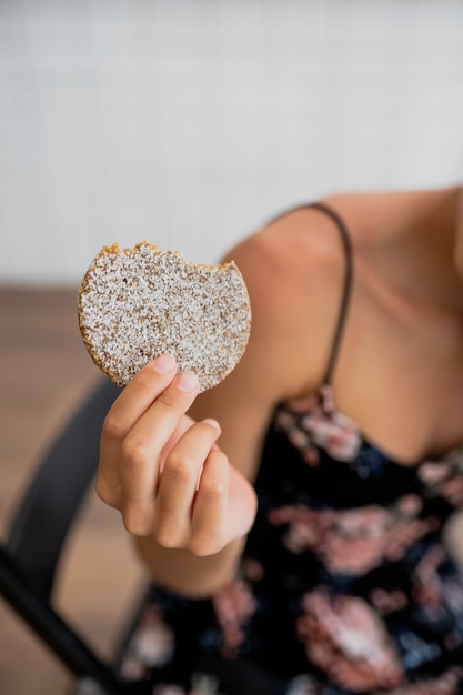 Feliz niña sonriente sostiene galletas en un acogedor café. Cerrar vista