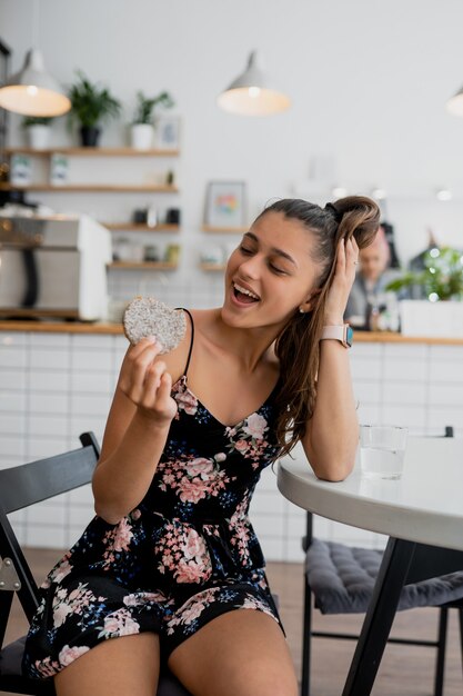 Feliz niña sonriente sostiene galletas en un acogedor café.