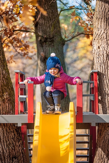 Feliz niña de tres años en la chaqueta en la diapositiva