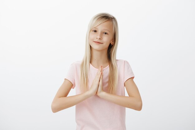 Feliz niño lindo, mujer rubia diciendo gracias con las manos juntas, gesto de namaste