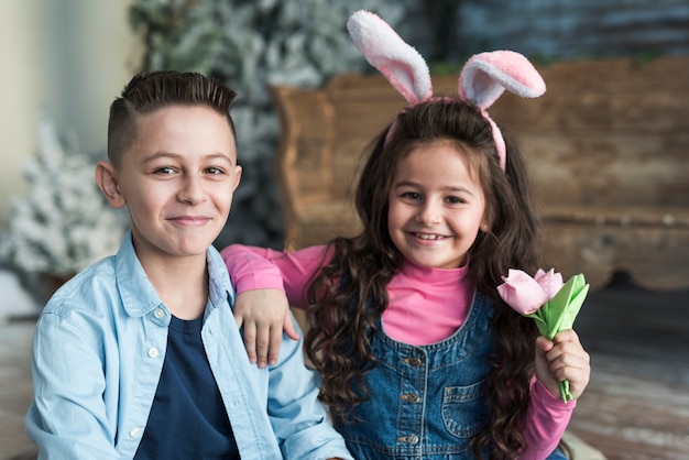 Feliz niño y niña en orejas de conejo con tulipanes