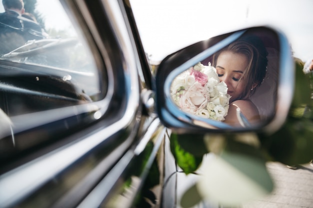 Feliz novia huele flores en el coche