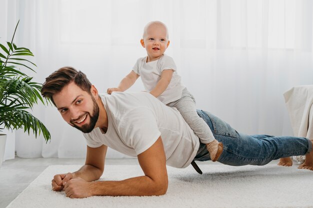 Feliz padre y bebé jugando juntos en casa