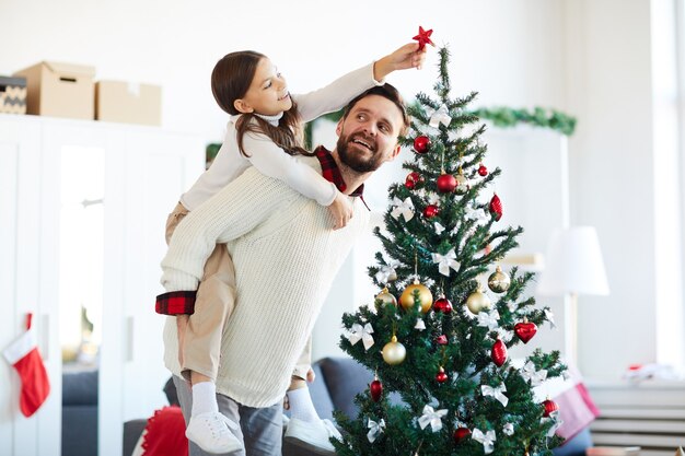 Feliz padre e hija decorando el árbol de Navidad