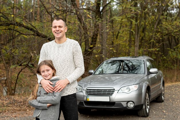 Feliz padre e hija de pie delante del coche