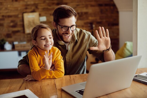 Feliz padre e hija saludando mientras tienen videollamadas en casa