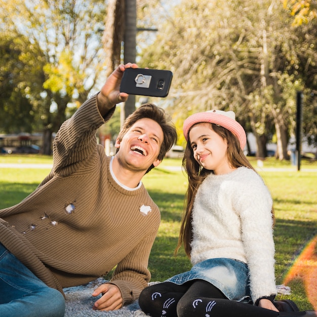 Foto gratuita feliz padre e hija teniendo selfie con teléfono móvil