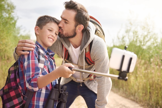 Feliz padre e hijo tomando selfie durante el senderismo