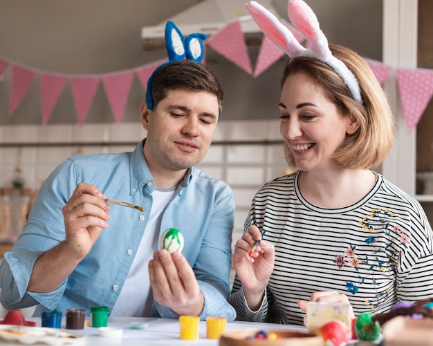 Feliz padre y madre pintando huevos de pascua