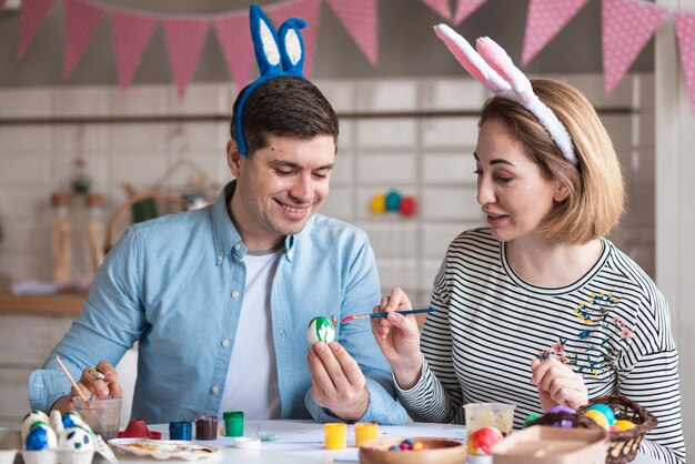 Feliz padre y madre pintando huevos de pascua