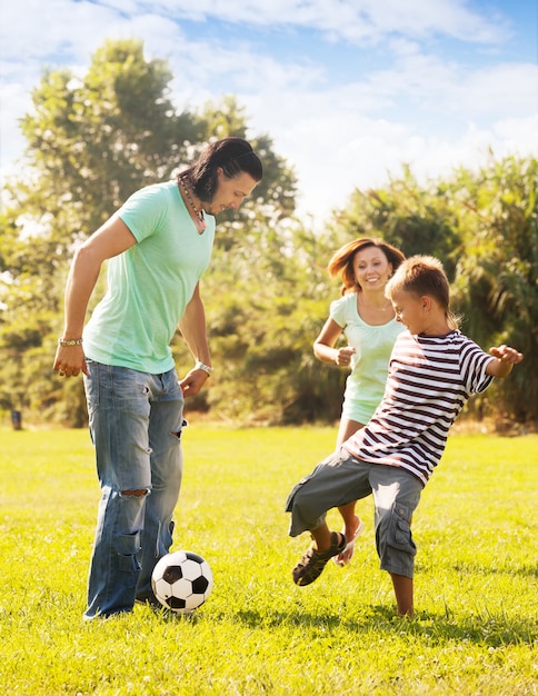 Feliz padres con hijo adolescente jugando con la pelota