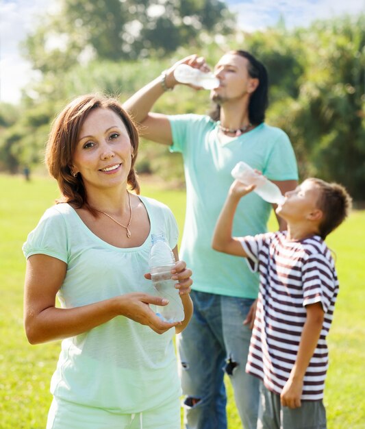 Feliz pareja con adolescente bebiendo botellas