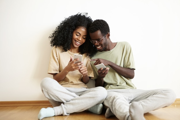 Feliz pareja africana joven vestida casualmente divirtiéndose juntos en casa