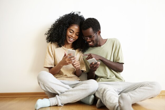 Feliz pareja africana joven vestida casualmente divirtiéndose juntos en casa