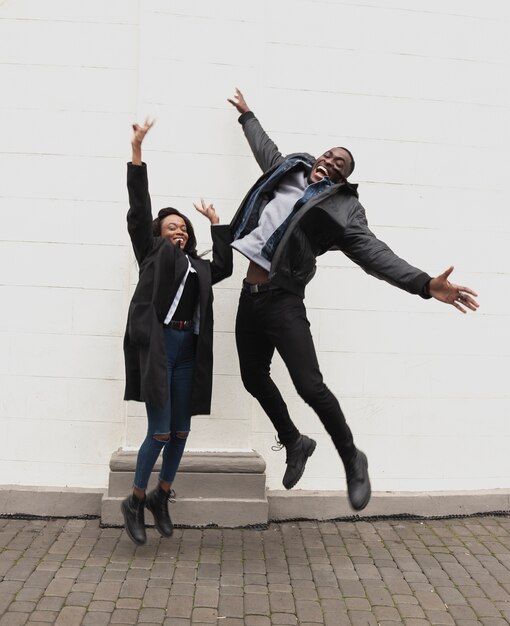 Feliz pareja afroamericana saltando tiro completo