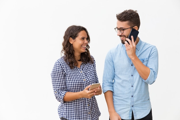 Foto gratuita feliz pareja alegre usando teléfonos móviles