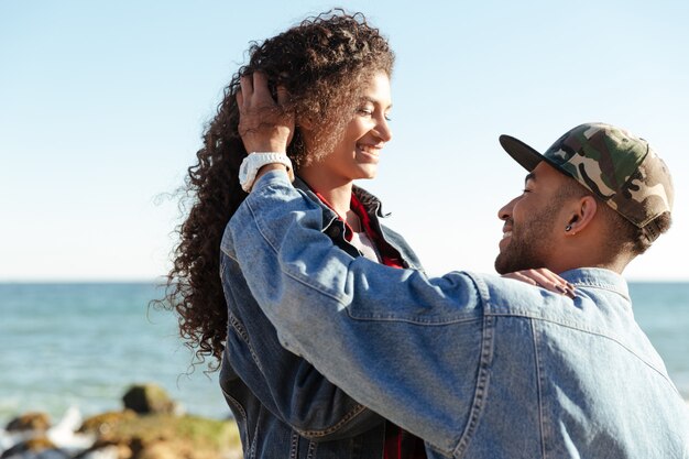 Feliz pareja amorosa africana caminando al aire libre en la playa