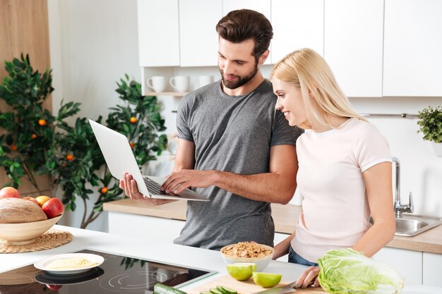 Feliz pareja amorosa joven de pie en la cocina y cocinar