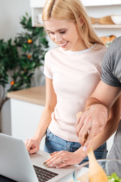 Feliz pareja amorosa joven de pie en la cocina