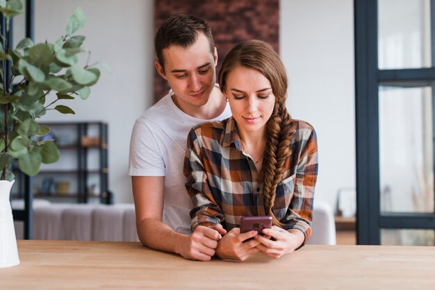 Feliz pareja amorosa viendo el teléfono en casa