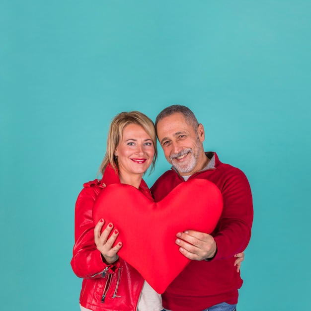 Feliz pareja de ancianos con gran corazón rojo