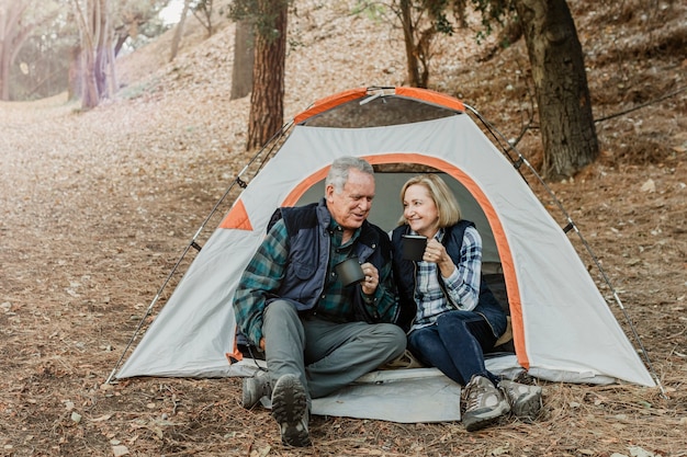 Feliz pareja de ancianos tomando un café en la carpa en el bosque