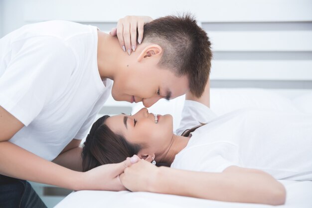 Feliz pareja asiática en la cama en su casa