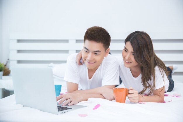 Feliz pareja asiática en la cama en su casa