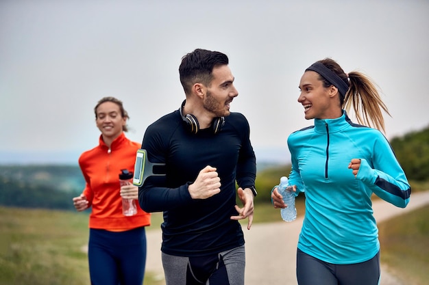 Feliz pareja atlética comunicándose mientras toma parte en un maratón en la naturaleza