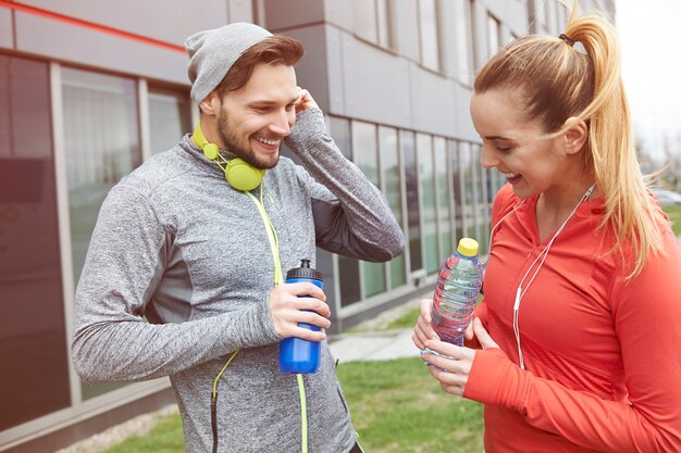 Feliz pareja bebiendo agua después del ejercicio