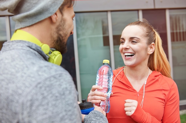 Feliz pareja bebiendo agua después del ejercicio