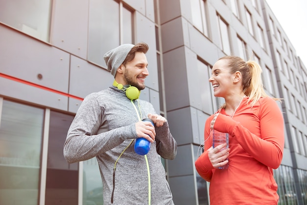 Feliz pareja bebiendo agua después del ejercicio