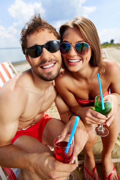 Feliz pareja bebiendo cócteles en la playa