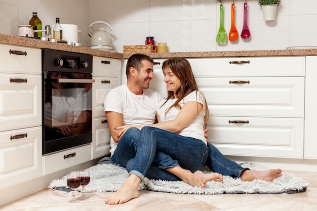 Feliz pareja bebiendo vino y sentado en el piso