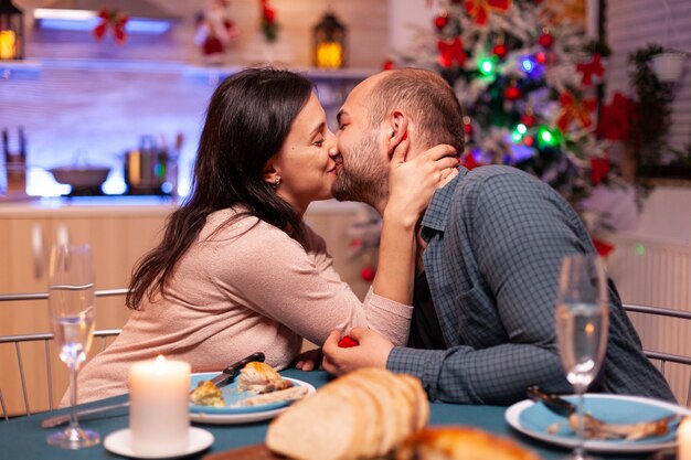 Feliz pareja besándose en la cocina de Navidad después de la propuesta de matrimonio