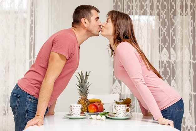 Foto gratuita feliz pareja besándose sobre una mesa
