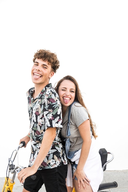 Feliz pareja en bicicleta contra la pared blanca burlas