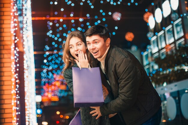 La feliz pareja con bolsas de compras disfrutando de la noche en la ciudad