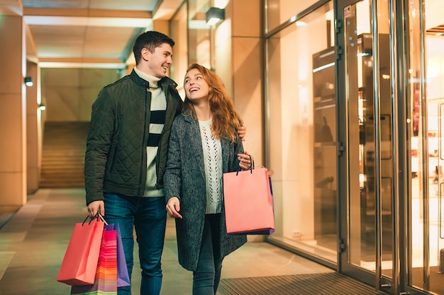 feliz pareja con bolsas de compras disfrutando de la noche en la ciudad