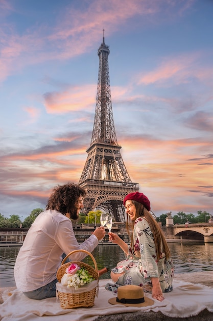 Una feliz pareja brinda frente a la Torre Eiffel