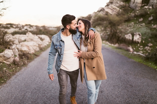 Foto gratuita feliz pareja caminando por una carretera