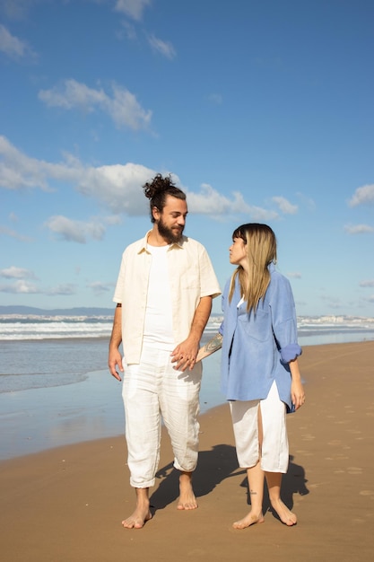 Feliz pareja caucásica paseando por la orilla del mar