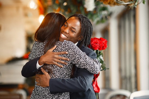 Feliz pareja celebrando su compromiso en un café y abrazándose fuertemente