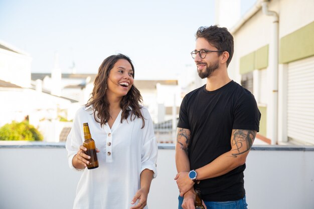 Feliz pareja charlando, riendo y bebiendo cerveza