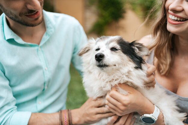 Feliz pareja de chicos jugando con su perro en el patio trasero sobre la hierba. Perro viejo alegre